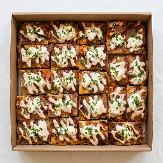 Focaccia Pizza Box (10pc) from Double Dribble — golden focaccia pizza squares with melted cheese, aioli and chives, cut into shareable pieces in a kraft catering box